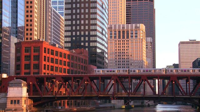 The El train travels over a bridge in front of the Chicago skyline.