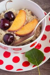 Breakfast Beauty. Milk oatmeal porridge with peaches and cherrie