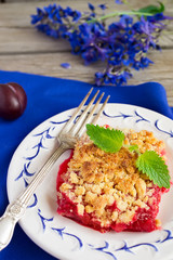Plum crumble on the wooden background with blue flowers, selecti