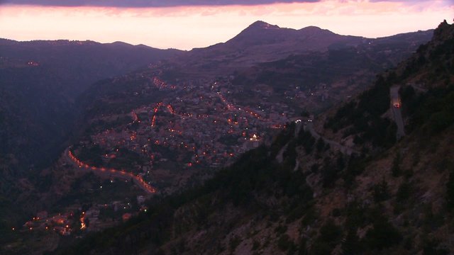 Cars drive up steep roads in the beautiful hills of Lebanon at dusk.