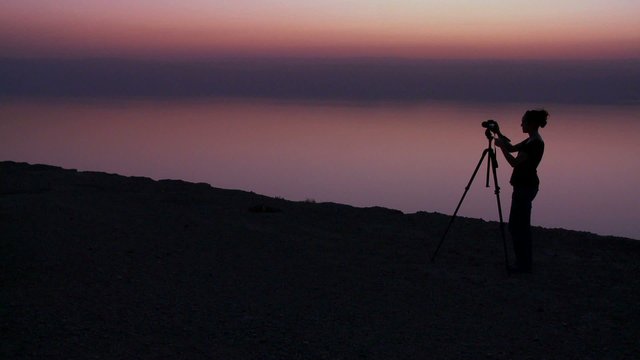 A photographer takes pictures in a purple golden glow after sunset behind the Dead Sea in Jordan.