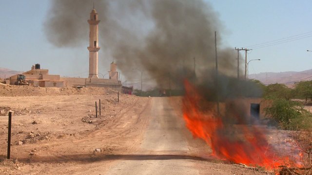 A fire burns on a lonely road near a mosque in the Palestinian Territories.