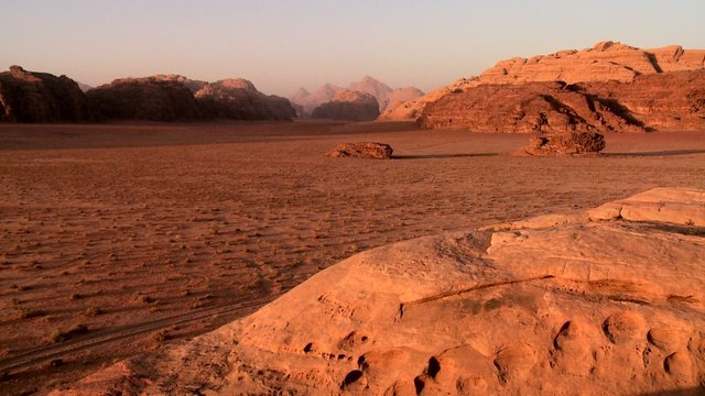 A wide establishing shot of the vast desert sands of Wadi Rum, Jordan.