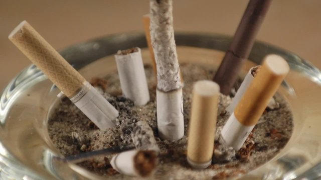A time lapse of a cigarette burning among stubs in an ashtray.