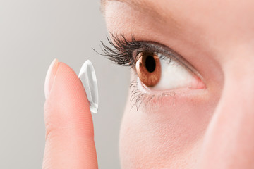Woman inserting a contact lens in eye.