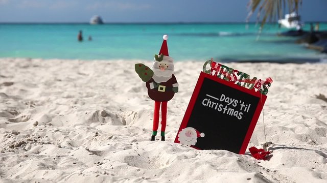 Christmas board on white sandy beach, with inscription - One day till Christmas, Tourism concept
