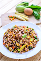 Fried rice with eggs and vegetables on white dish.