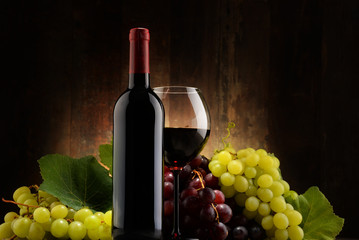 Composition with glass, bottle of red wine and fresh grapes