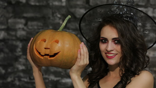 A woman-sorceress covers her face pumpkin