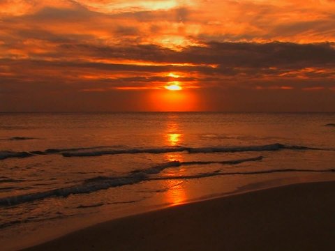 Beach waves slowly break during sunset.