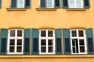 Fototapeta na wymiar Windows with shutters on yellow wall 