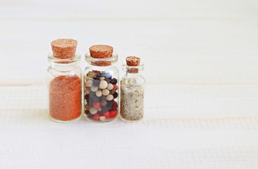 Spices and herbal sea salt in glass kitchen bottles, condiment shelf, empty wooden background, soft focus