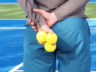 Ball kid holding several Tennis balls behind his back at blue artificial grass court, Melbourne, Australia 2015