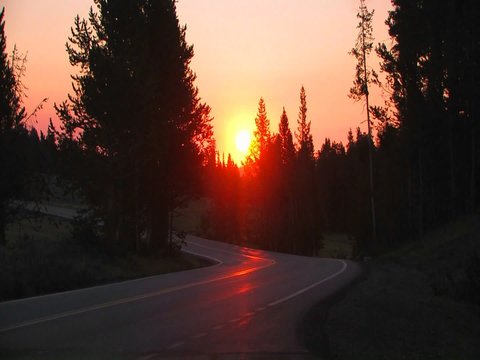 Sunrise over a road with a Subaru passing.