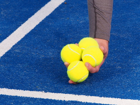 Tennis balls picked up by a ball kids hand on a blue artificial grass court, Melbourne, Australia 2015