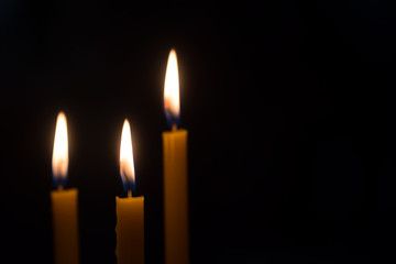 yellow candle lit on black background.