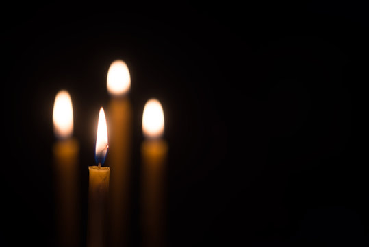 yellow candle lit on black background.