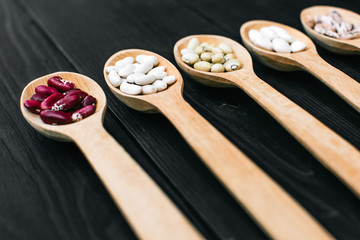 A colorful of beans in wood spoon on wood background