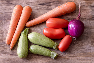 onion, tomatoes, carrot and zucchini on wood