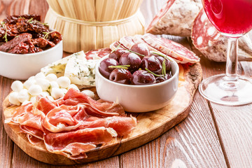 Wine snack set. Variety of cheese and meat on dark background.