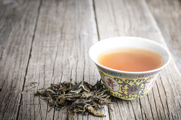 teapot on a wooden table with leaves of tea