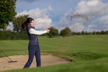 Golferin spielt einen Ball aus dem Bunker