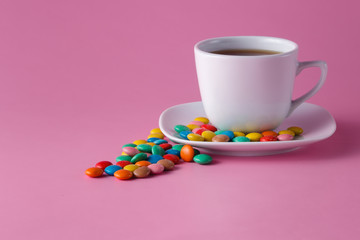 tea cup with colored sweet dragees on saucer