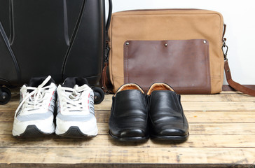 Black leather shoes, Sport shoes  and  luggage travel bag on the