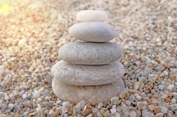 Fototapeta na wymiar Stack of zen stones on beach background with burning sun