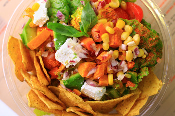 Healthy Mexican salad in a plastic bowl with nachos shot close-up from above