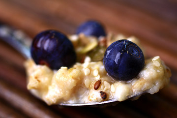 Healthy porridge and blueberries spoonful shot on a wooden background