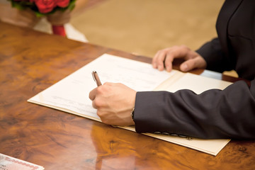 Bridegroom puts his signature to the document Certificate of Mar