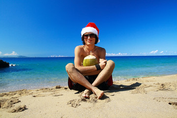 Santa Claus with green coconut fruit on beach of ocean