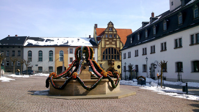 Osterbrunnen/Auf dem Marktplatz einer Kleinstadt in Th&uuml;ringen ist zu Ostern der Brunnen mit vielen bunten Ostereiern geschm&uuml;ckt, im Hintergrund H&auml;user und das Rathaus.