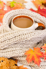 Obraz na płótnie Canvas Cup of coffee and warm scarf on wooden background with autumn l