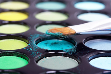 Professional makeup brush on eyeshadows palette, closeup
