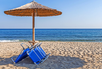 Sunbed, straw umbrella on beautiful beach background