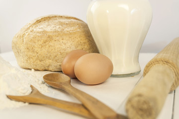 Fototapeta na wymiar Fresh baked bread and ingredients for cooking, eggs, milk, flour