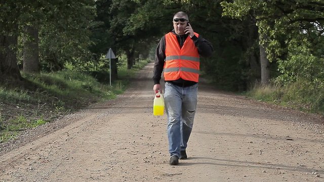 Man with cell phone and  plastic can on rural road 