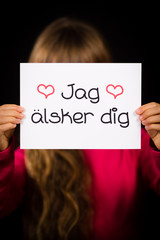 Child holding sign with Swedish words Jag Alsker Dig - I Love Yo