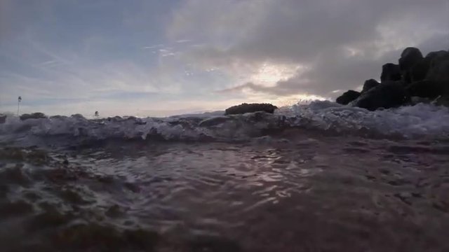 Water level view of waves crashing and rolling into shore in slow motion.