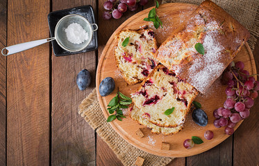 Juicy and tender cupcake with plums and grapes. Top view