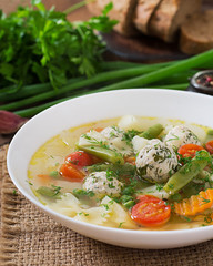 Diet vegetable soup with chicken meatballs and fresh herbs in bowl