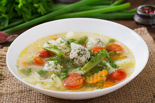 Diet vegetable soup with chicken meatballs and fresh herbs in bowl