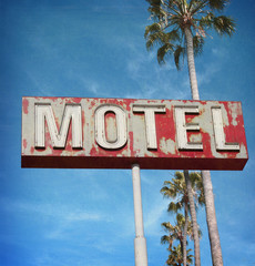 aged and worn vintage photo of neon motel sign with palm trees