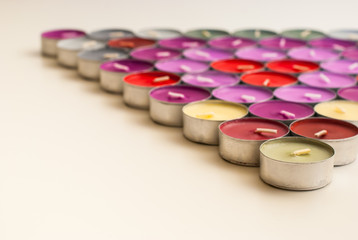 Colored Tea Candles Arranged to Triangle Shape on White Desk