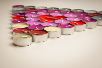 Colored Tea Candles Arranged to Triangle Shape on White Desk