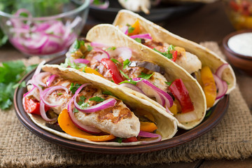 Mexican tacos with chicken, grilled vegetables and red onion.