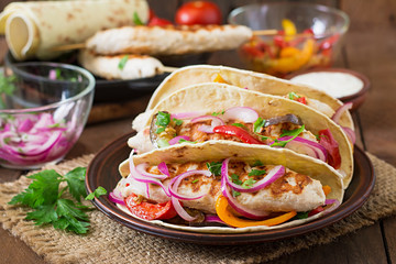 Mexican tacos with chicken, grilled vegetables and red onion.