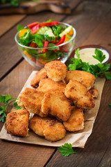 Chicken nuggets and sauce on a wooden background © timolina
